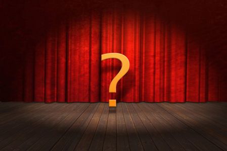 A yellow question mark floats above a wooden stage with a red theatre curtain 